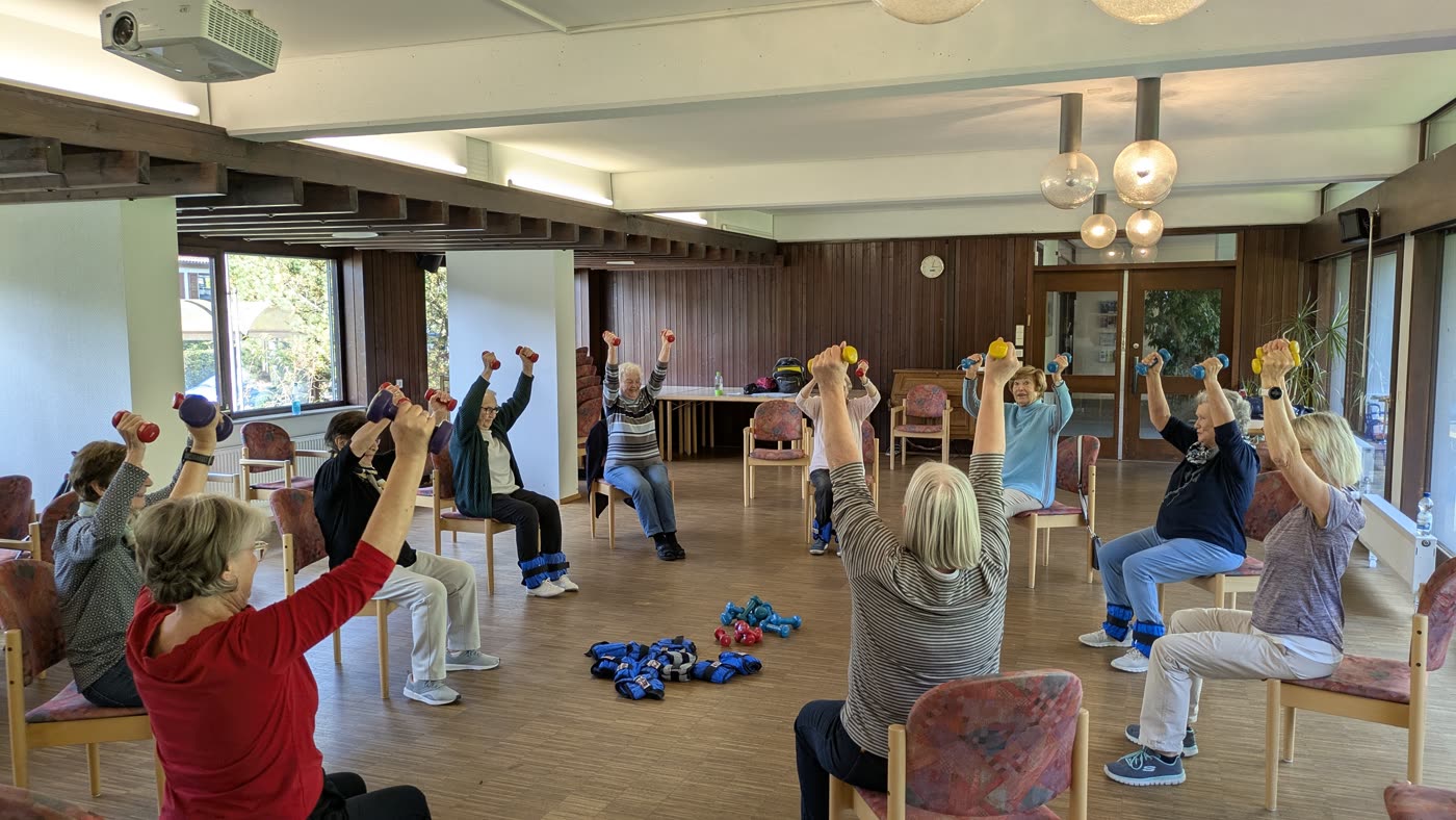 Gruppe beim Kraft- und Balancetraining mit Hanteln im Saal